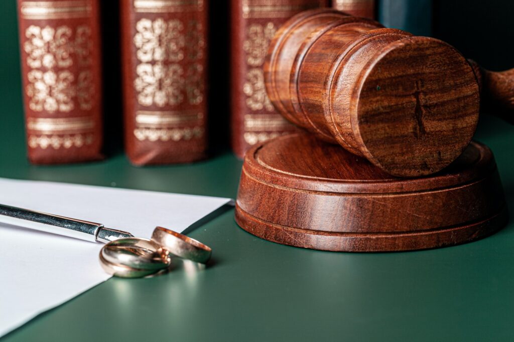 Law gavel and wedding rings on table